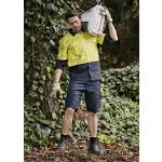 Men's rugged cooling vented shorts in navy, styled with a bright yellow shirt, set against a leafy background.