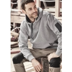 A grey unisex multi-pocket hoodie is worn by a man seated on a wooden bench, with worksite equipment in the background.