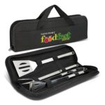 A black BBQ tool set case containing stainless steel spatula, tongs, and basting brush with a logo on the front.
