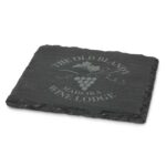 A single slate coaster in dark grey with a grapevine design and a logo. Edges are textured and natural.